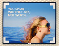 Another HP ad, showing a female in the foreground, wind blowing her hair, deep blue water behind her, and the phrase 'You speak with pictures, not words.'